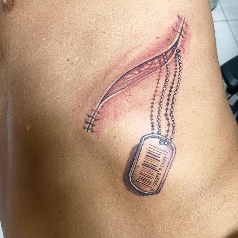 persona con tatuaje de medalla saliendo de una cicatriz