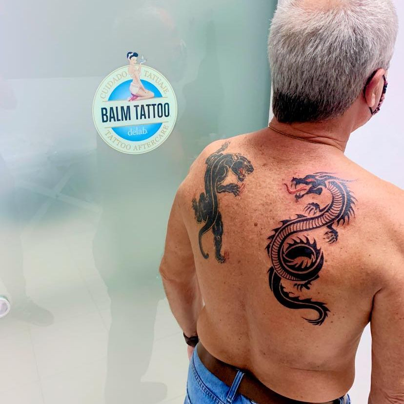 persona con tatuaje de dragón y pantera en la espalda